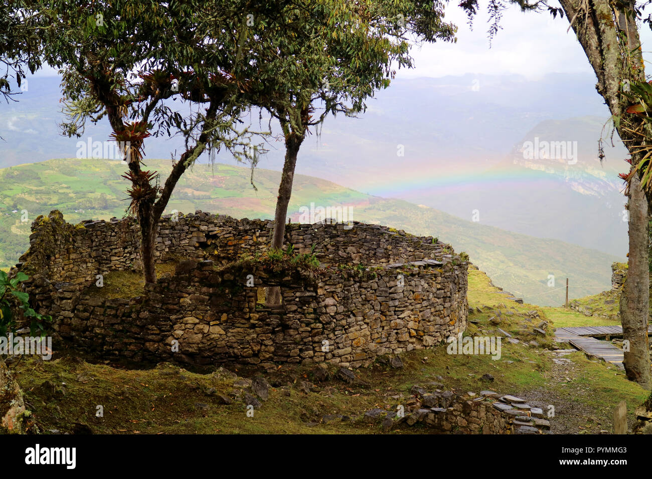 Die Bäume innen wachsende abgerundete Haus Ruinen von Kuelap Berges eine Zitadelle mit der Regenbogen der unteren Hügel im Hintergrund, nördlichen Peru Stockfoto