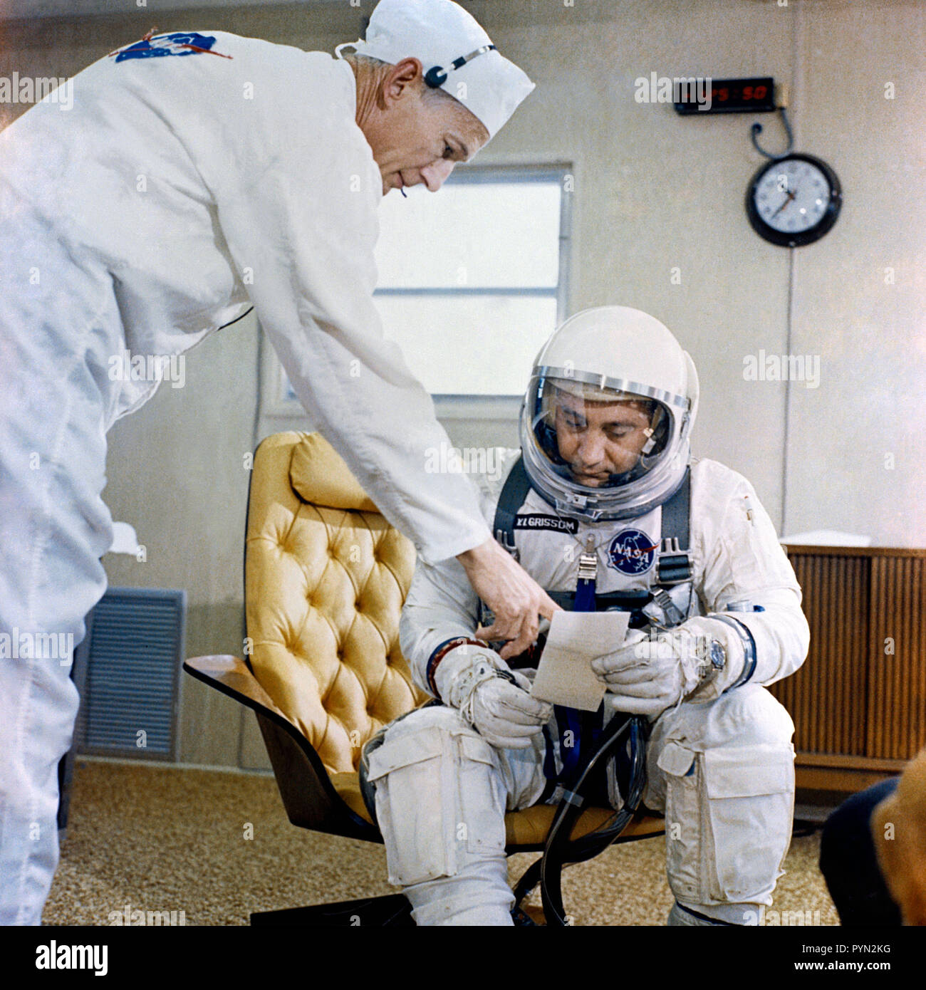 (23 März 1965) - - - I. Astronaut Virgil Grissom, Befehl Pilot des Gemini-Titan 3 space flight, ist in die passende Anhänger an Pad 16 gezeigt über eine Checkliste mit Anzug Techniker Joe Schmitt. Stockfoto
