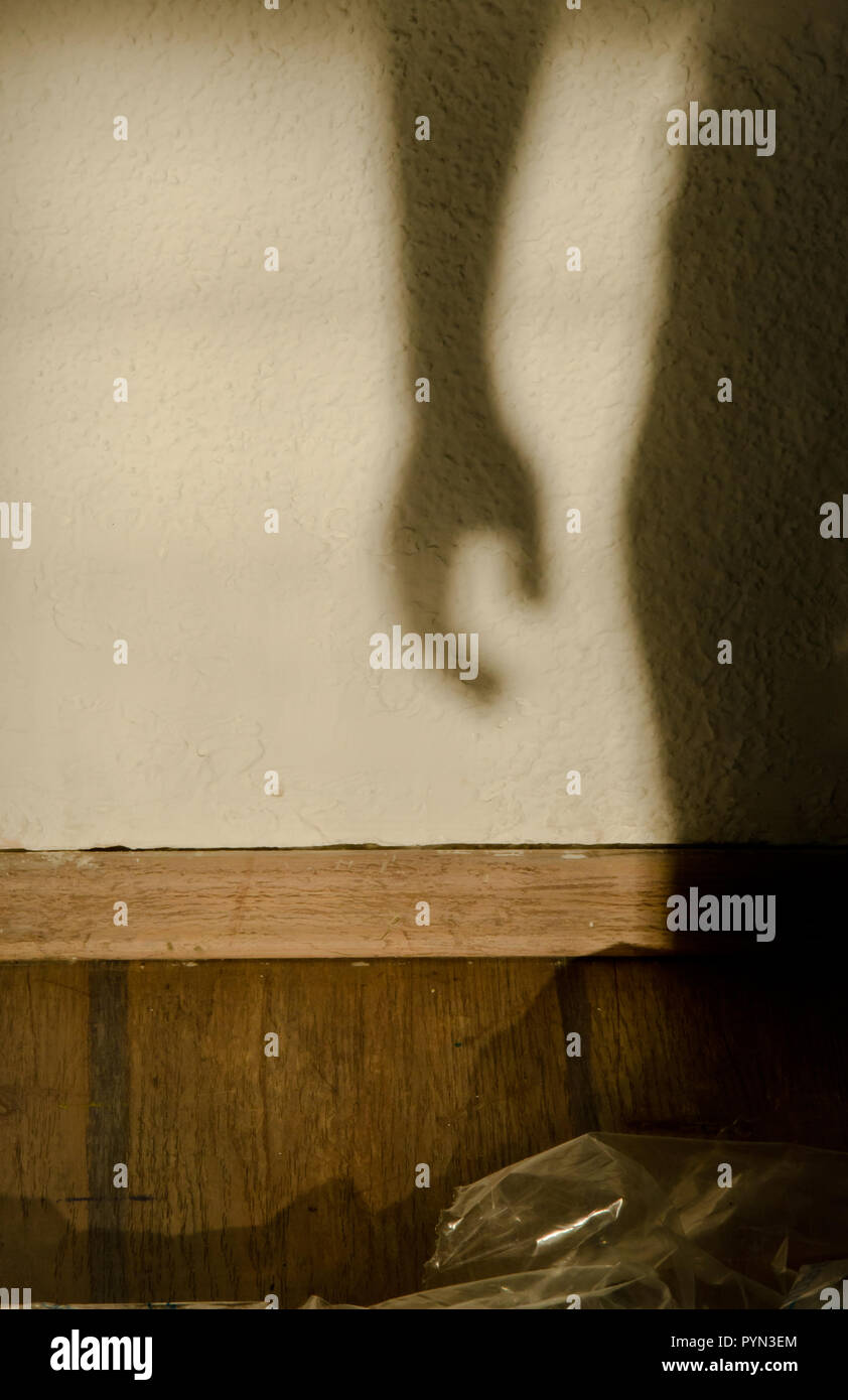 Schatten der Hand und Teil des Körpers an der Wand in den leeren Raum bei Sonnenuntergang Stockfoto