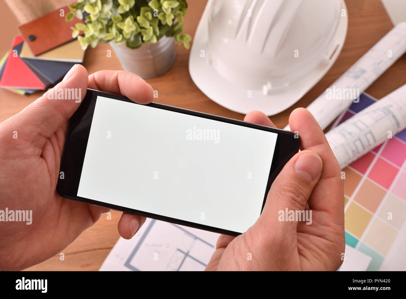 Hände mit Smartphone ansehen multimedia Inhalte mit Bezug zum Bau in einem Büro. Top View Stockfoto