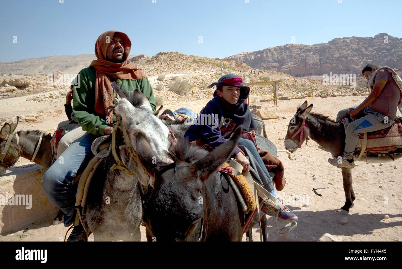 Bedouin Männer und Jungen neigen dazu, ihre Esel, Pferde und Kamele, Fahrten für Touristen in der Petra Archäologischen Park zu bieten, in Jordanien am 29. Oktober 2018 Stockfoto