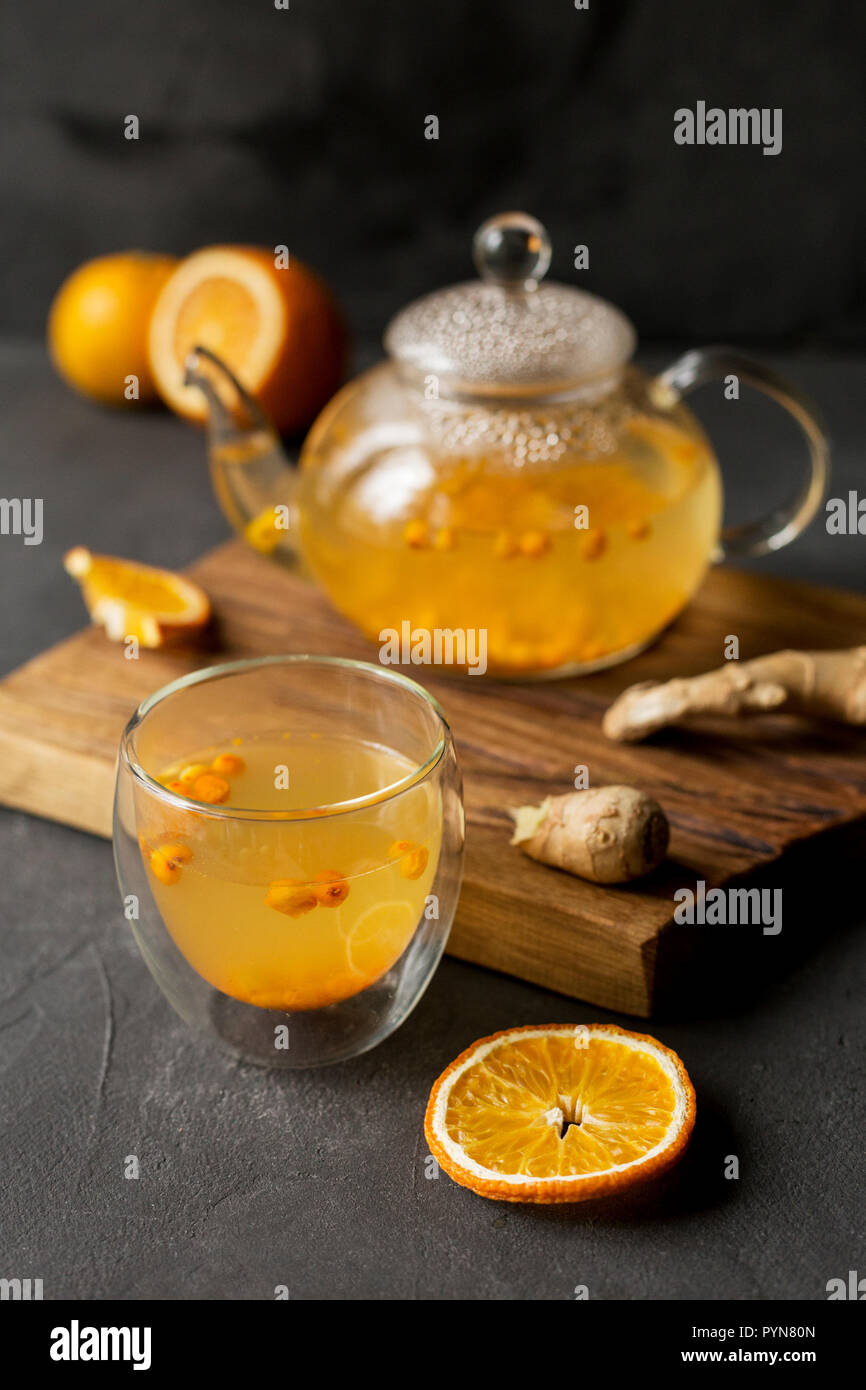 Warme Meer buck Thorn Tee Teekanne aus Glas mit Glas Schale, Orange und  Ingwer in der Nähe, auf Holzbrett auf schwarzem Hintergrund Stockfotografie  - Alamy