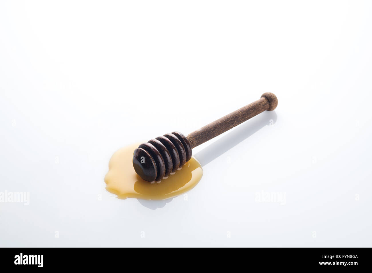 Braun Holz- Honig Pendelarm mit Goldgelben Honig auf weißem Hintergrund Stockfoto