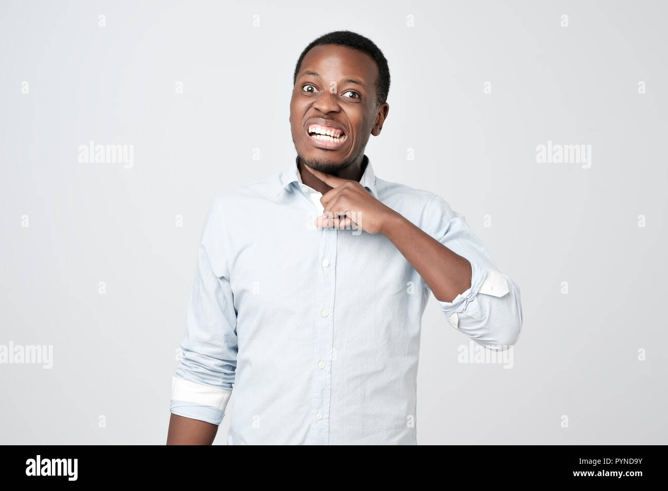Afrikanischer mann Grimassen von Zorn, die Finger in der Nähe von Hals, imitiert Messer, schneiden Kehle Stockfoto
