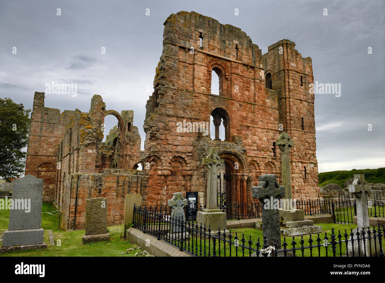 Vordere von Lindisfarne Kirche Ruinen des mittelalterlichen Klosters mit Regenbogen arch und Friedhof Grabsteine auf der heiligen Insel von Lindisfarne England Großbritannien Stockfoto