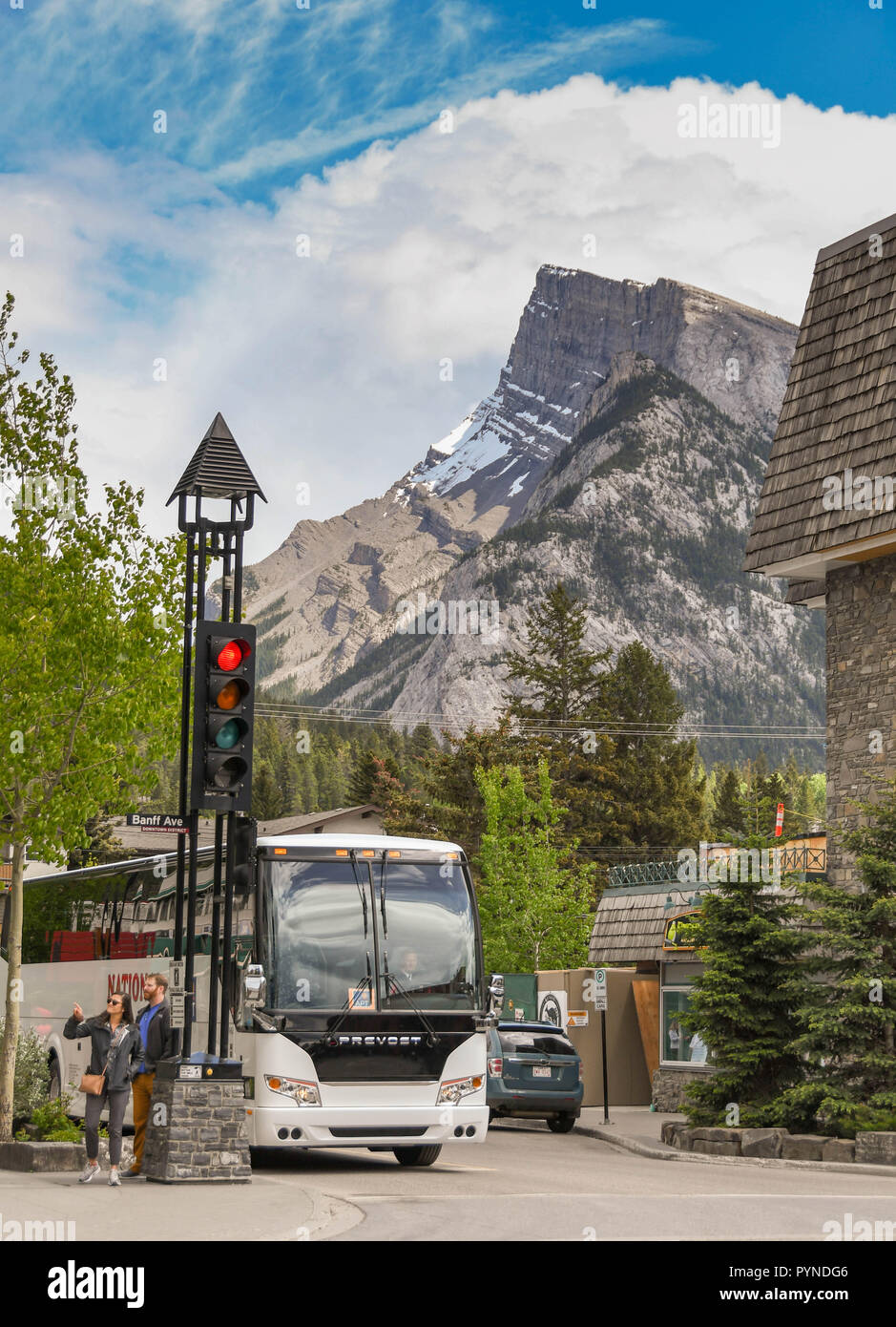 BANFF, AB, Kanada - Juni 2018: Ausflug mit dem Bus in einer Seitenstraße in Banff Stadtzentrum mit hoher Berg im Hintergrund geparkt. Stockfoto