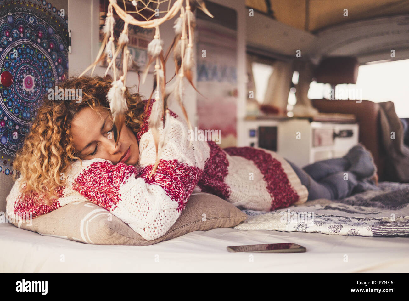 Frau mit lockigem Haar und gestreiften Pullover Schlafen und Träumen auf Home van, von der Meeresbrise wiegen. Konzept der Unabhängigkeit, Erholung, reisen, le Stockfoto