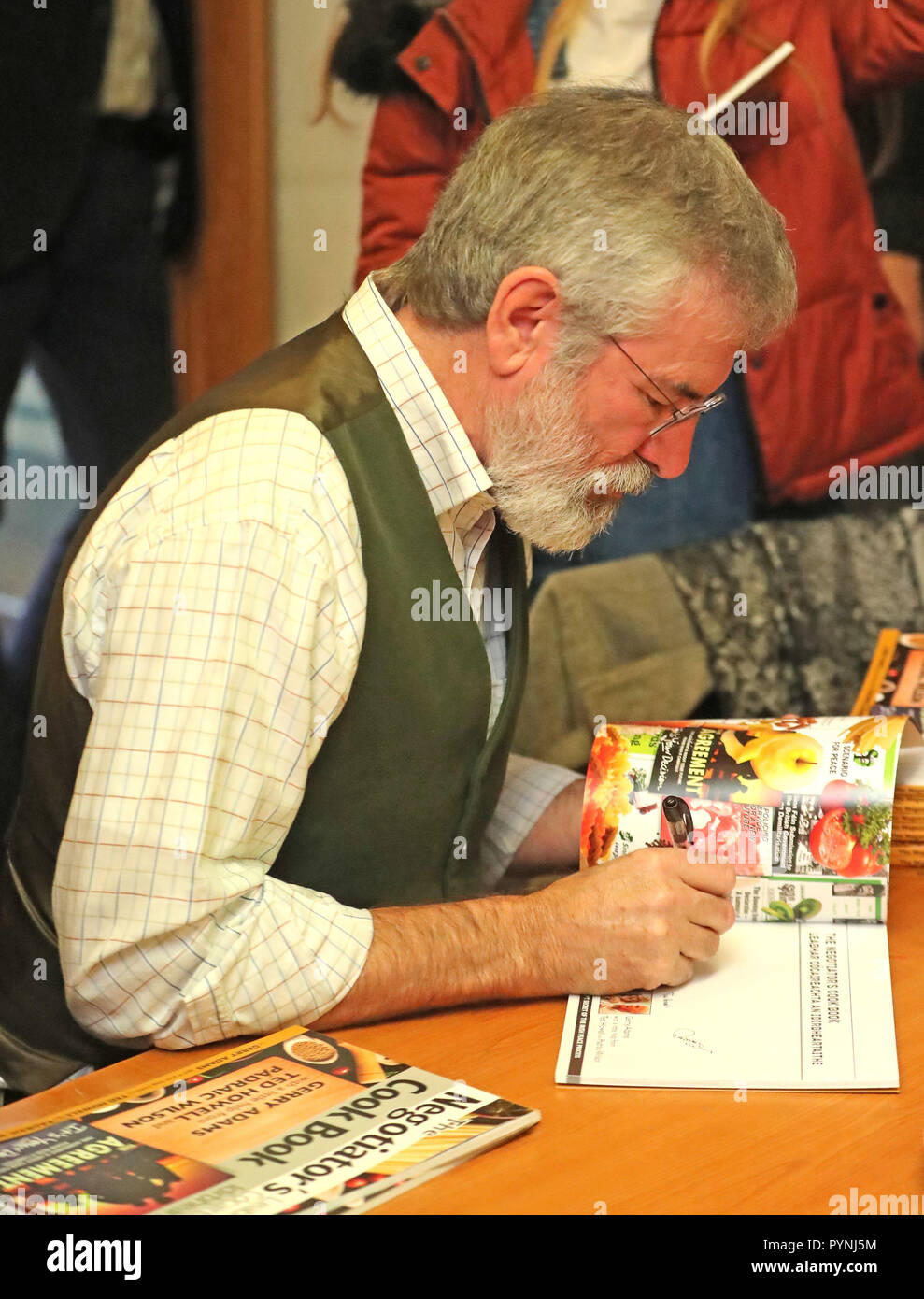 Der ehemalige Sinn-Fein-Anführer Gerry Adams signiert Kopien seines Rezepturbuches mit dem Titel The Negotiators' Cookbook im Culturlann on the Falls Road in Belfast. Stockfoto