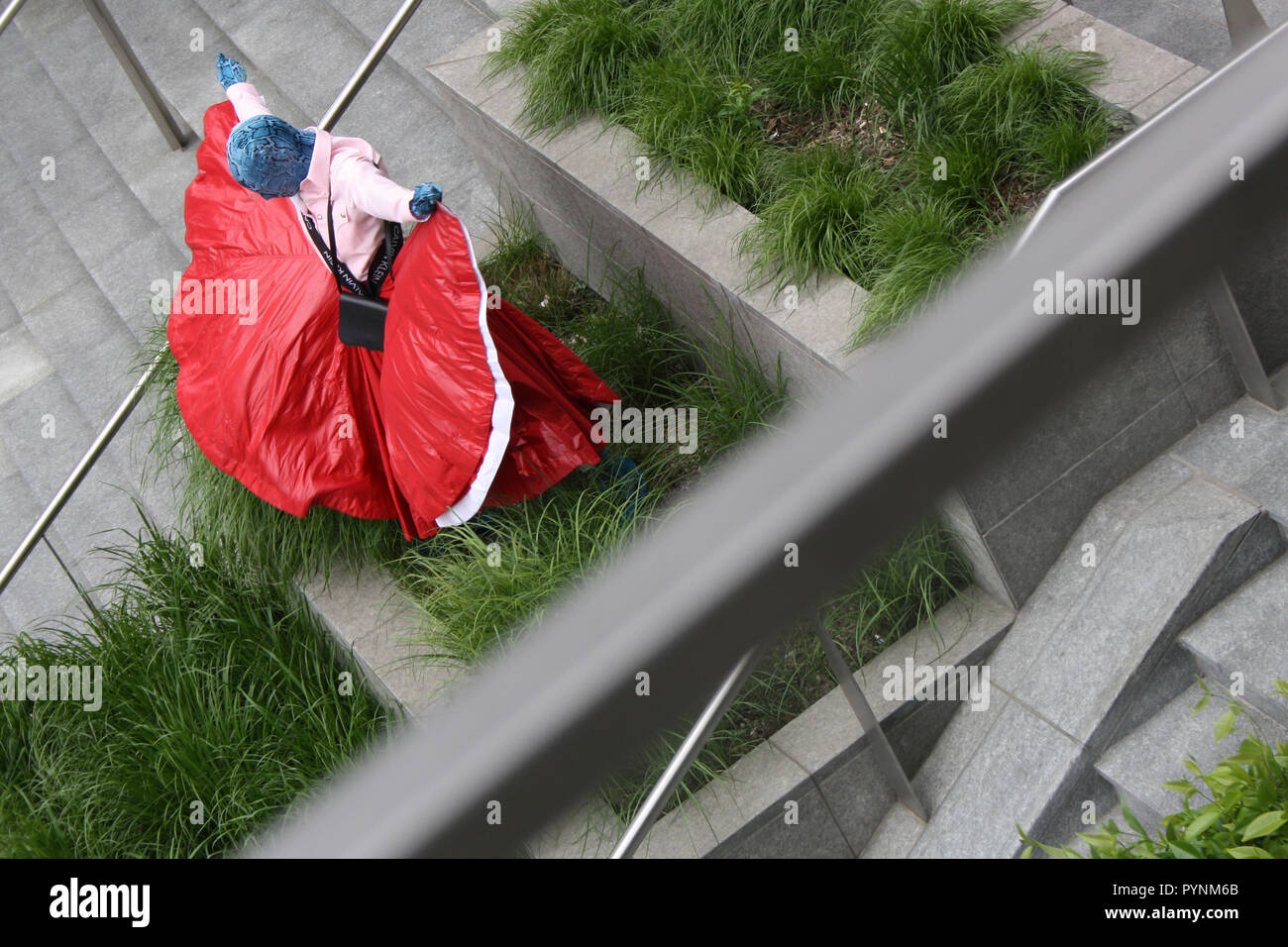 Ein Mädchen im roten Kleid performas künstlerische Leistung im öffentlichen Raum. Sehr stilvoll und Leistung in der Mitte von Mailand Stadt mutig. Stockfoto