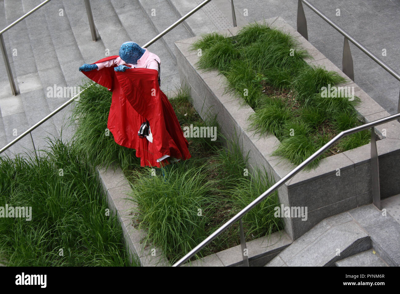 Ein Mädchen im roten Kleid performas künstlerische Leistung im öffentlichen Raum. Sehr stilvoll und Leistung in der Mitte von Mailand Stadt mutig. Stockfoto