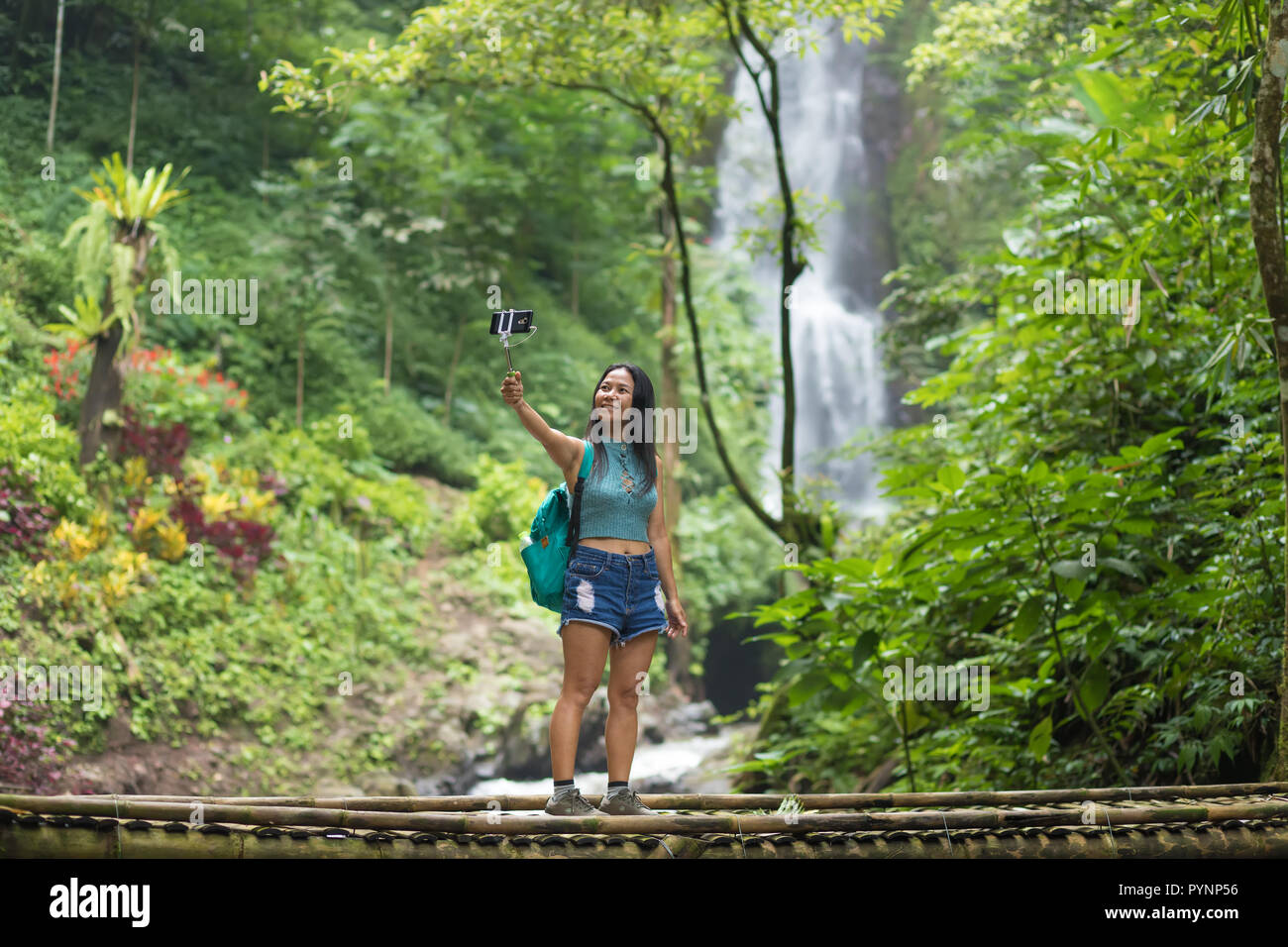 Touristische Frau eine selfie auf einem Bambus Brücke in der Nähe des Red Coral Munduk Wasserfall im Dschungel, Bali, Indonesien Stockfoto