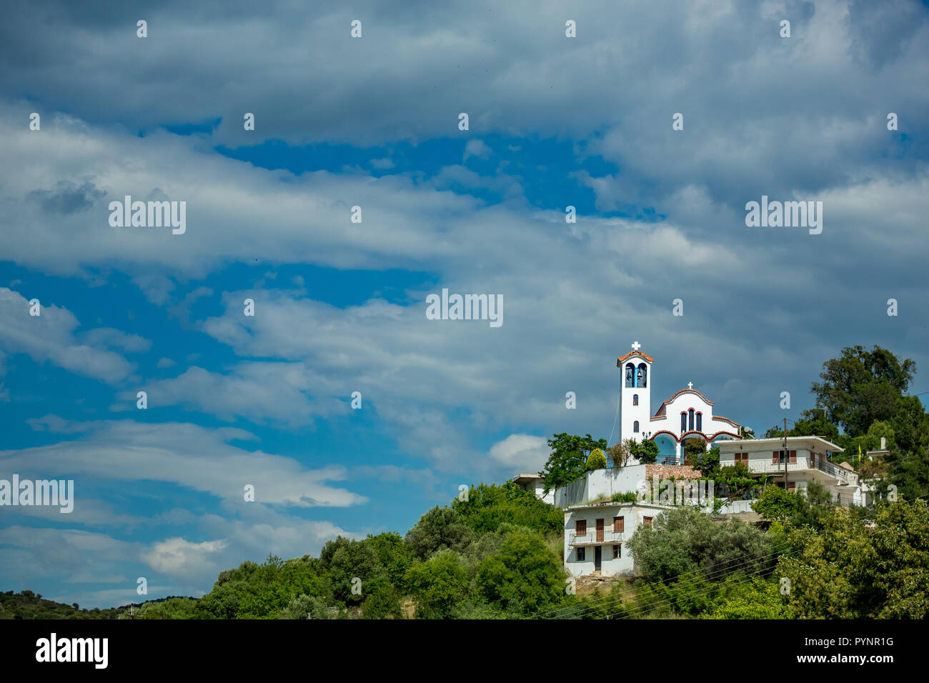 Feder tagsüber Landschaft mit Christlich-orthodoxen Kirche im Dorf der Mursi, Albanien. Landschaft bewölkten Himmel mit Gebäude auf der grünen Hügel Stockfoto
