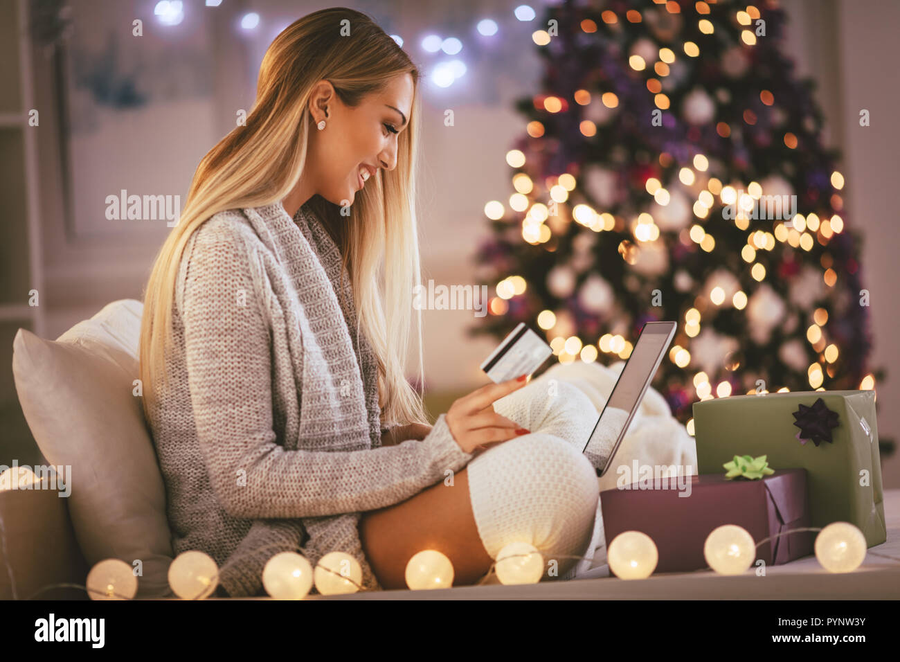 Glückliche junge Frau Entspannung zu Hause und online kaufen Weihnachtsgeschenke auf dem Laptop. Stockfoto