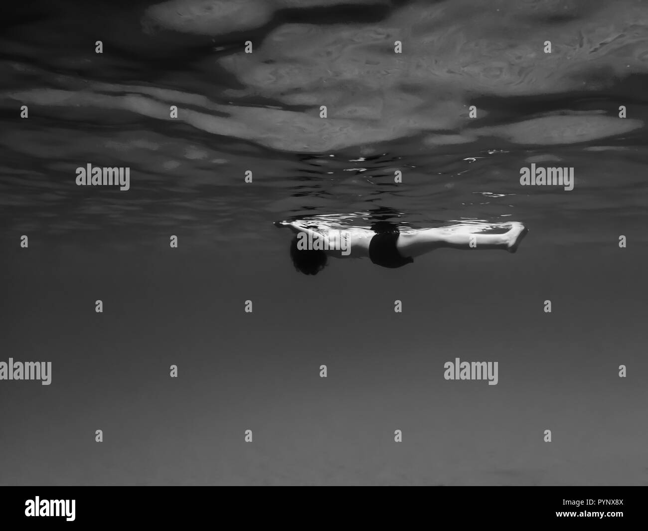 Frau schwimmend auf der Oberfläche des Meeres von Unterwasser in Schwarz und Weiß konzeptionelle Bild Stockfoto