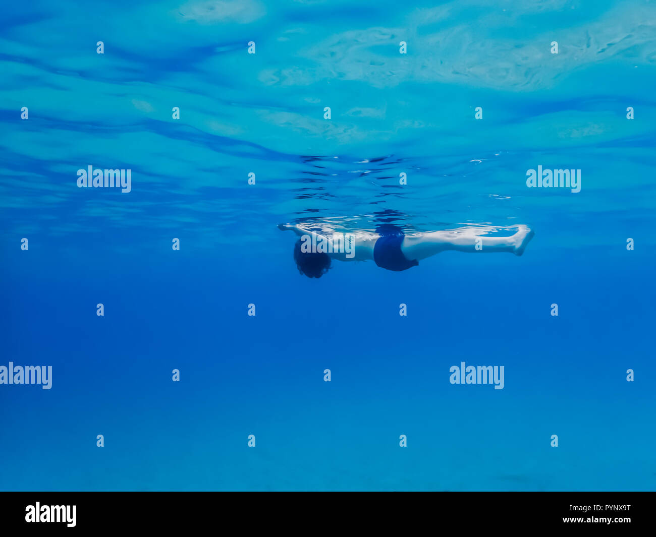 Frau schwimmend auf der Oberfläche des blauen Ozean von der Seite Winkel unterwasser Perspektive Stockfoto