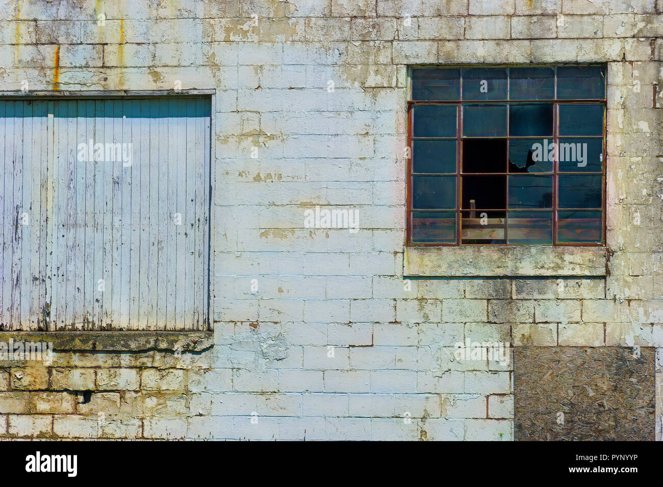 Ein heruntergekommenes Backsteingebäude mit kaputten Bügeleisen gerahmte Fenster einen abstrakten Hintergrund. Stockfoto