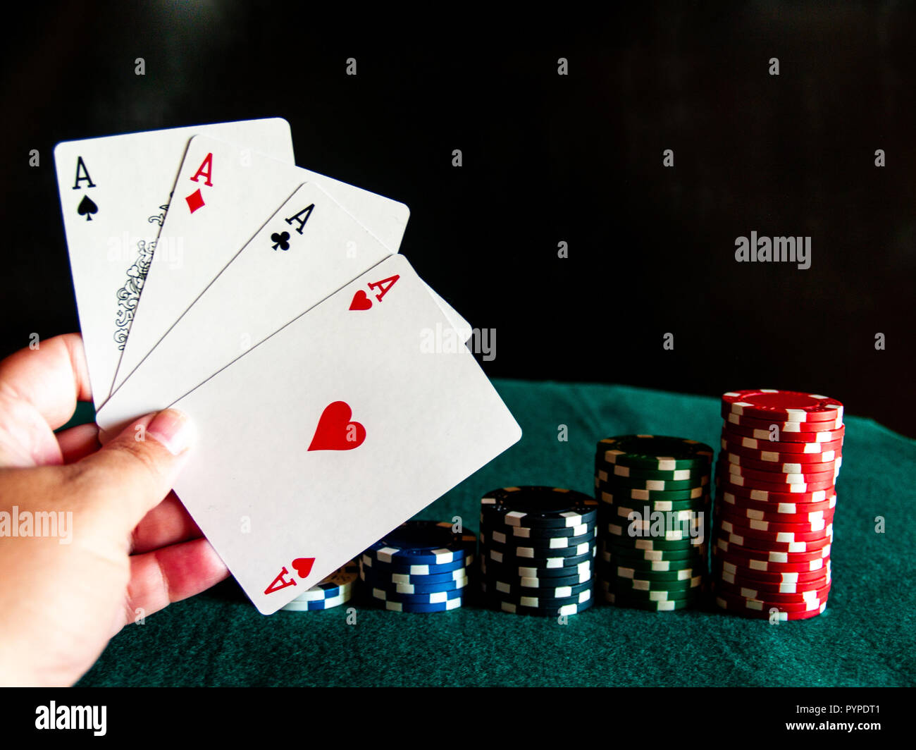 Eine Person spielen Poker mit den vier Asse der ein Deck in der Hand und poker chips in verschiedenen Farben auf der grünen Matte Stockfoto