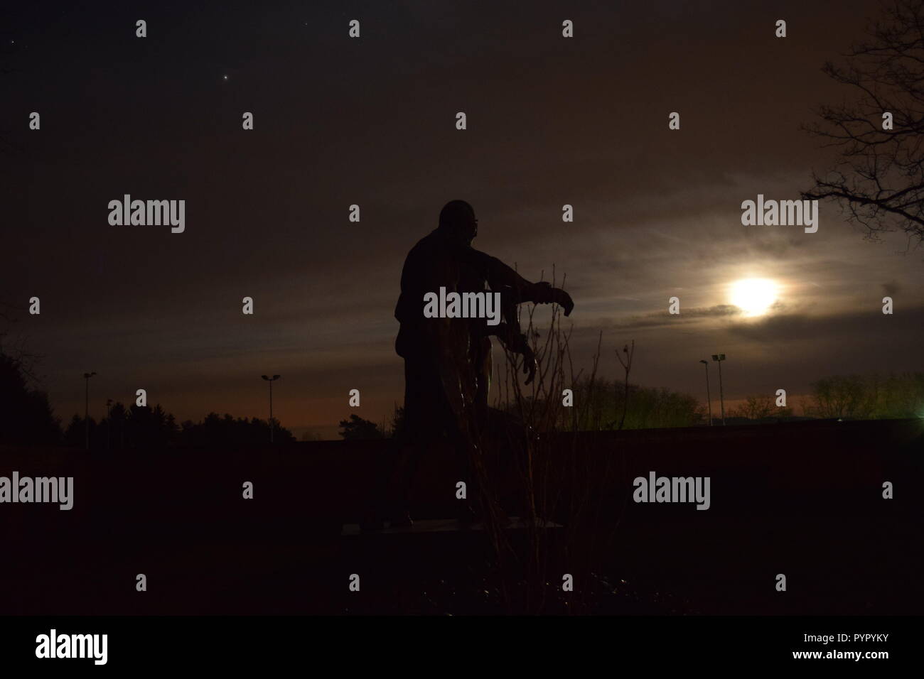 Timeline der aufgehenden Mond in der Nacht Dämmerung Himmel von einer Bronzeskulptur Silhouette in der soldatenfriedhof Reimsbach an der Saar Deutschland gesehen Stockfoto