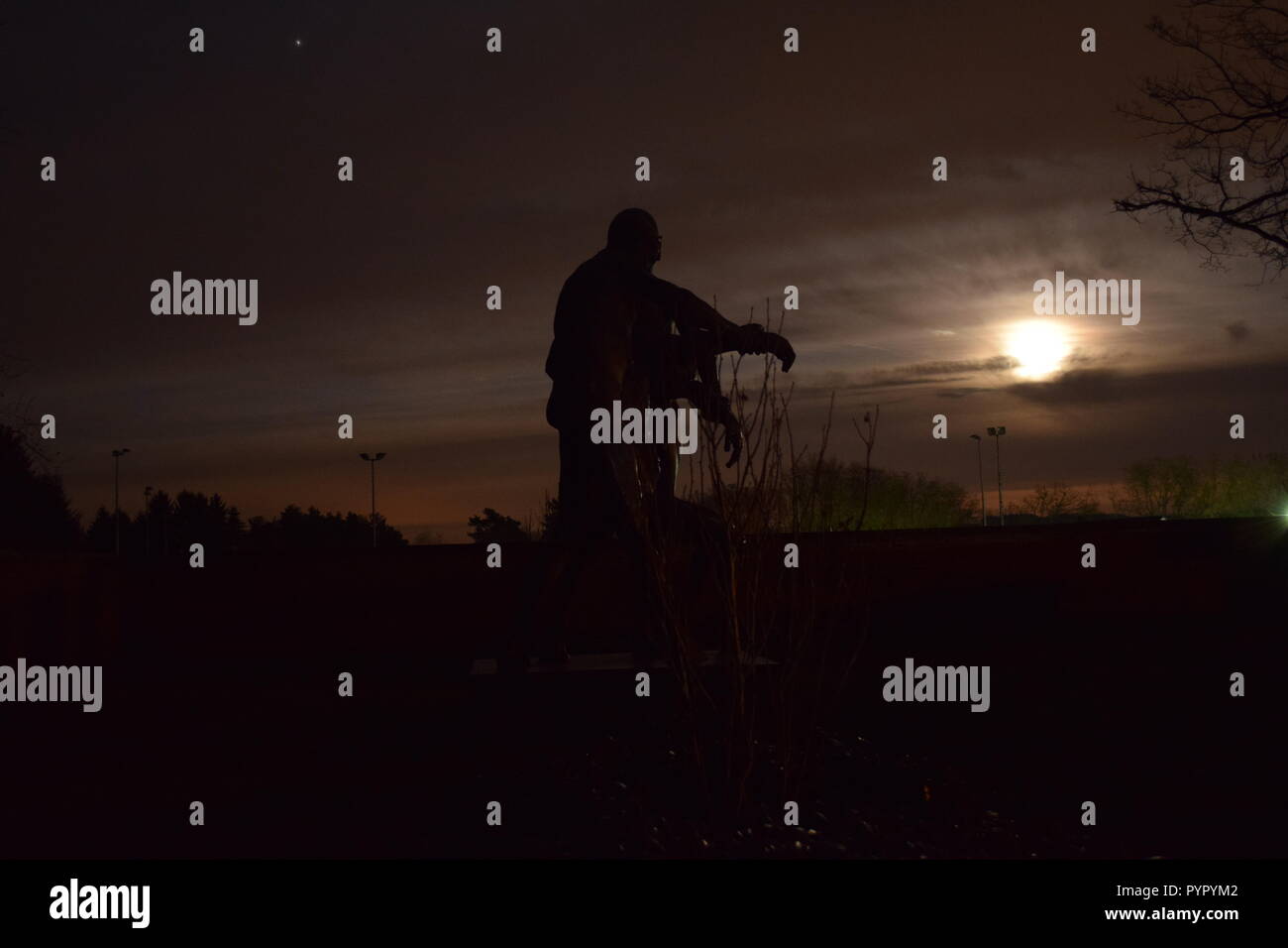 Timeline der aufgehenden Mond in der Nacht Dämmerung Himmel von einer Bronzeskulptur Silhouette in der soldatenfriedhof Reimsbach an der Saar Deutschland gesehen Stockfoto