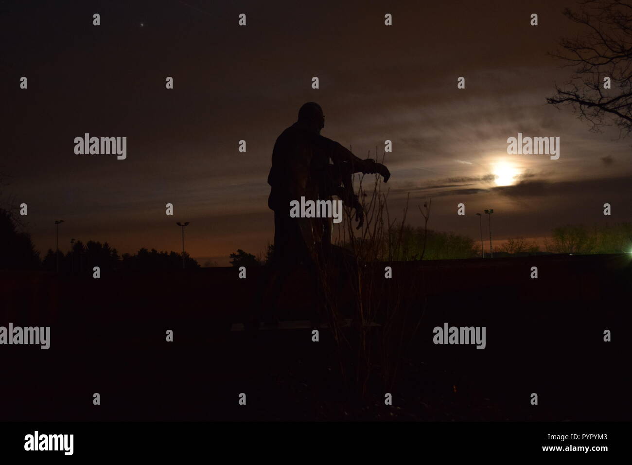 Timeline der aufgehenden Mond in der Nacht Dämmerung Himmel von einer Bronzeskulptur Silhouette in der soldatenfriedhof Reimsbach an der Saar Deutschland gesehen Stockfoto