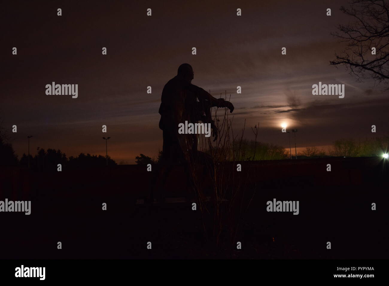 Timeline der aufgehenden Mond in der Nacht Dämmerung Himmel von einer Bronzeskulptur Silhouette in der soldatenfriedhof Reimsbach an der Saar Deutschland gesehen Stockfoto