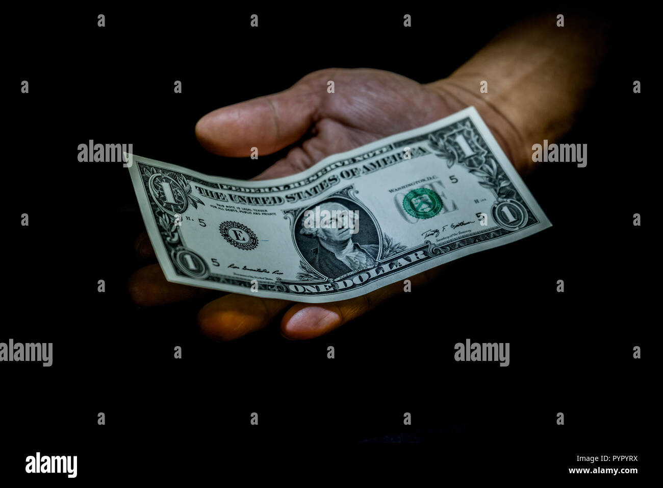Ein Dollar Bill in der Hand einer Person isoliert auf Schwarz. Konzept der Betteln für verlassen, armen, kleinen Lohn, Spenden, Impressum Stockfoto