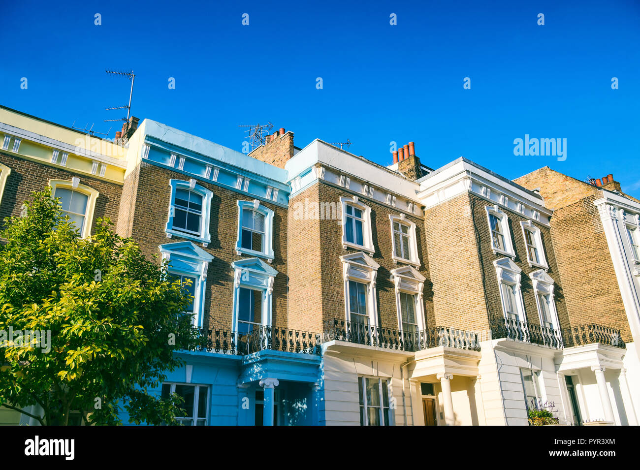 Classic Reihe von terrassenhäusern von traditionellen Gelb London Stock Backstein hell durch helle Sommer Sonne unter strahlend blauem Himmel Stockfoto
