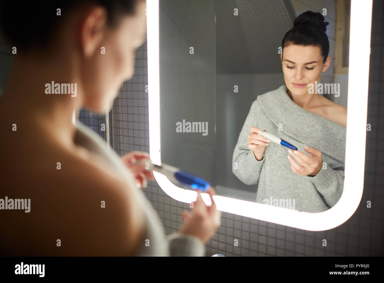 Ernsthafte Frau Kontrolle der Schwangerschaft Test im Badezimmer Stockfoto