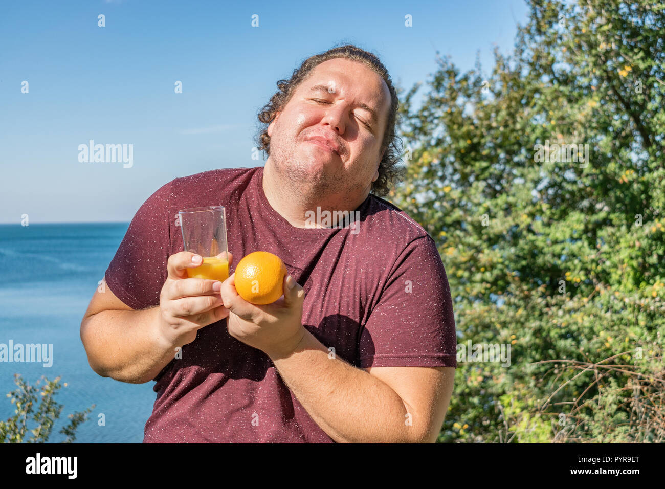 Funny Fat Man auf dem Ozean Saft trinken und Obst essen Stockfoto