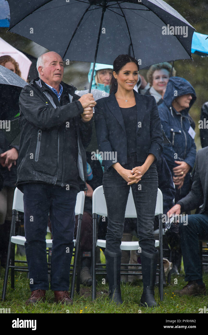 Die Herzogin von Sussex steht unter einem Sonnenschirm bei einem starken Regenguss von Regen zu einem Engagement von einer Fläche von Bush, the Queen's Commonwealth Vordach, Redvale auf dem North Shore, an Tag drei der Tour ist das königliche Paar von Neuseeland. Stockfoto