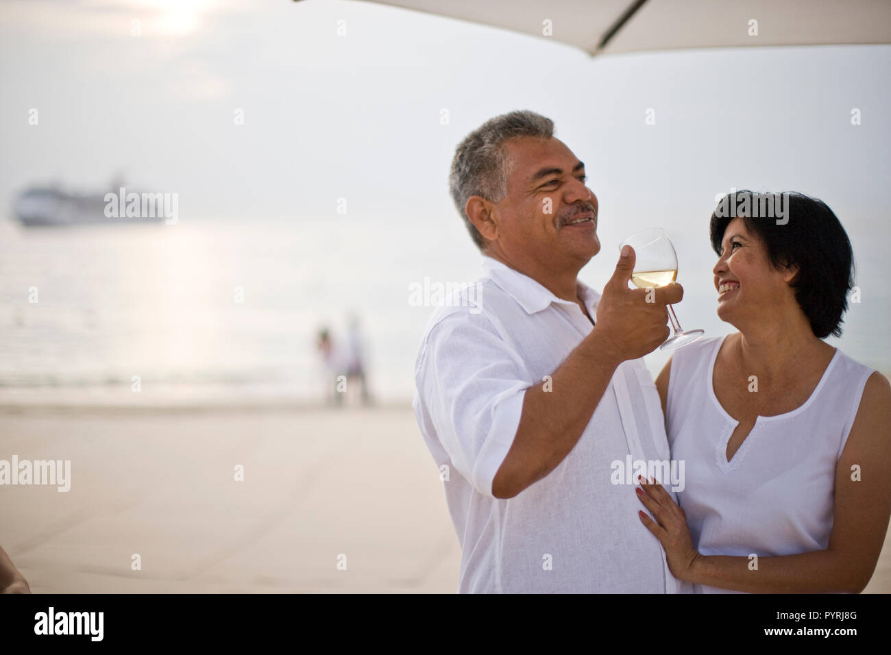 Älteres paar trinken Wein am Strand Stockfoto