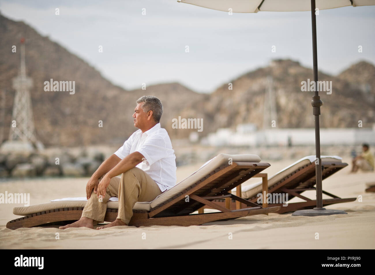 Mann sitzt auf der Liege am Meer Stockfoto