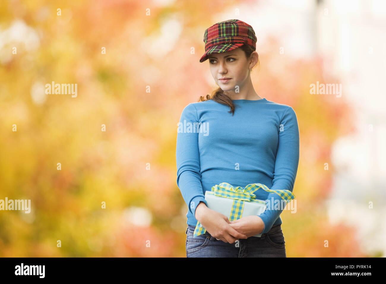 Junge Frau in eine karierte Kappe mit einem verpackten Geschenk mit einem Bogen nach außen gebunden. Stockfoto