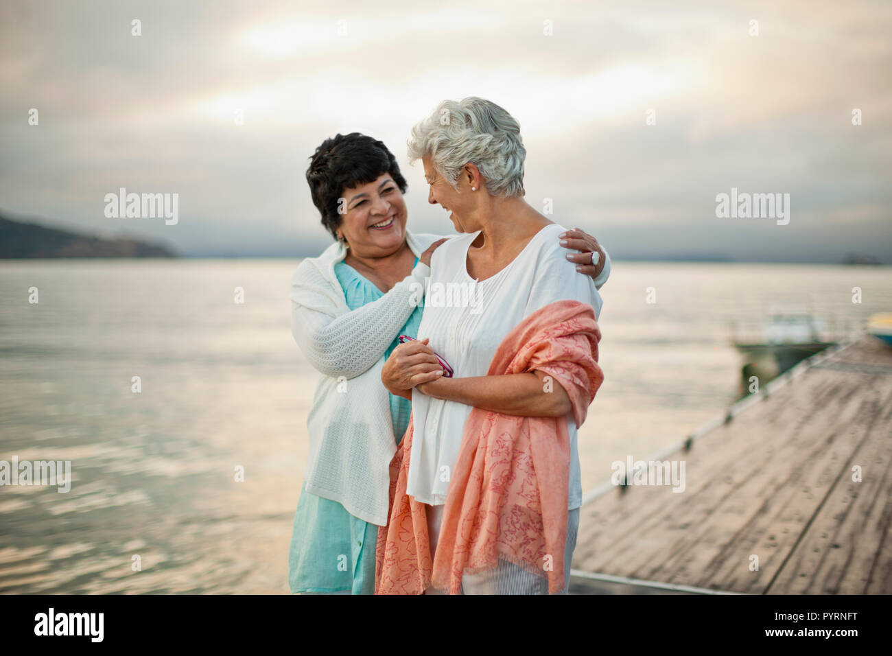 Zwei glückliche reife Frauen gemeinsam Spaß haben als Sie chatten und entlang einem Bootssteg entfernt. Stockfoto