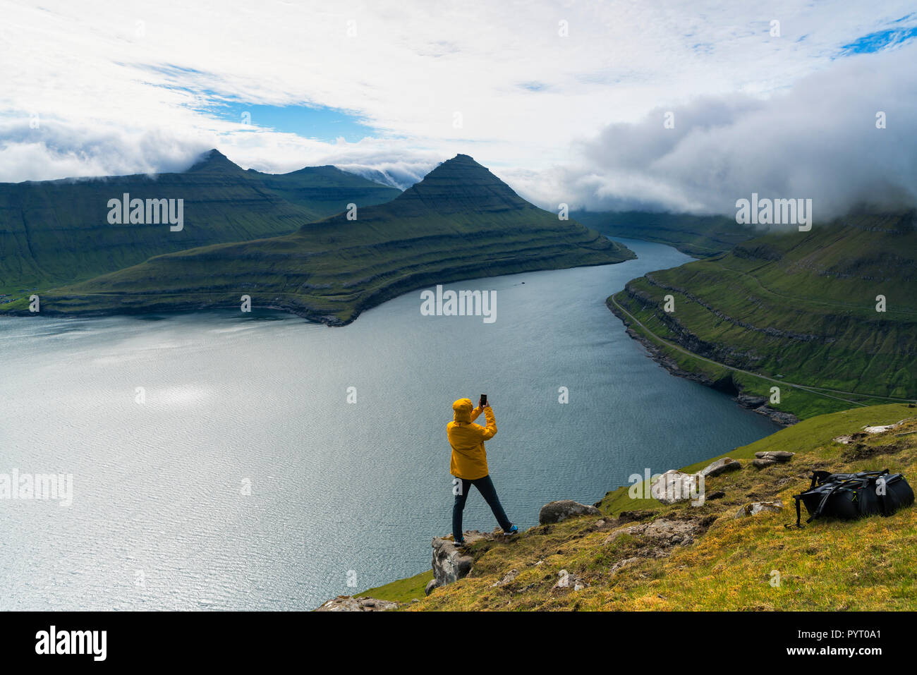 Wanderer mit Smartphone snaps Bilder von den Fjorden, Funningur, Eysturoy Island, Färöer, Dänemark Stockfoto