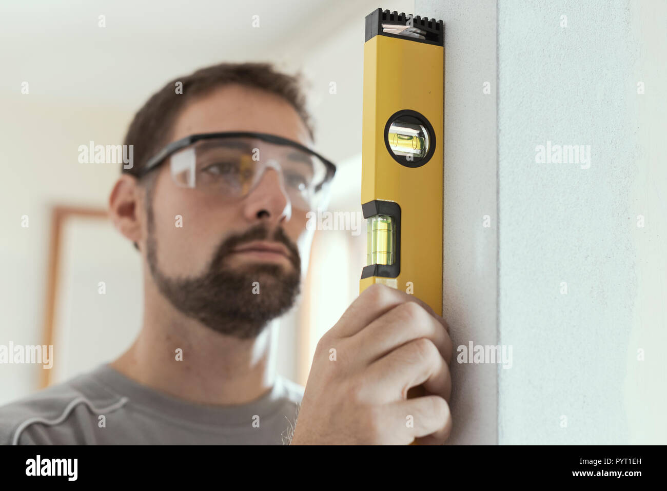 Mann mit Hilfe einer Wasserwaage eine Wand: Home Renovierung Konzept zu Plumb Stockfoto