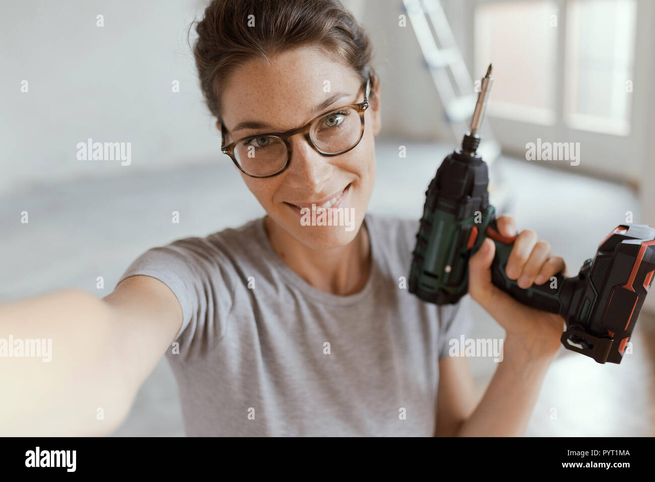 Gerne fröhliche Frau mit einer Bohrmaschine und einem selfie, Home Renovierung und tun es sich Konzept Stockfoto