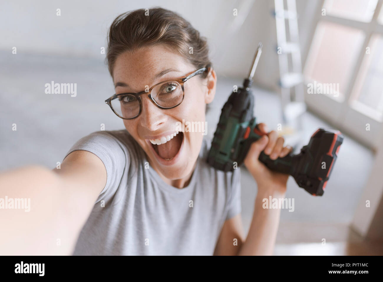 Gerne fröhliche Frau mit einer Bohrmaschine und einem selfie, Home Renovierung und tun es sich Konzept Stockfoto