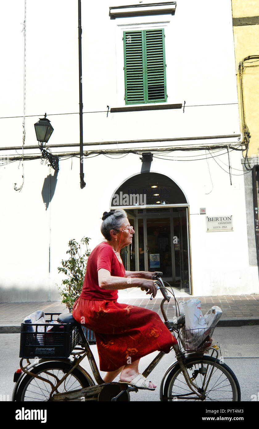 Eine ältere italienische Frau Radfahren auf der Via Guglielmo Oberdan in Pisa, Italien. Stockfoto