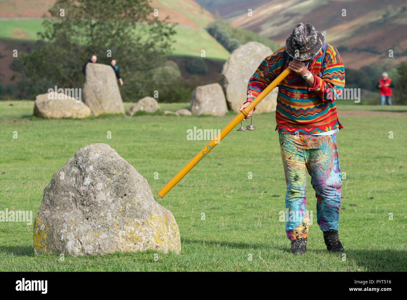 Neu - alter Mann bläst ein Didgeridoo in Richtung der Steine von Castlerigg Steinkreis im englischen Lake District, Cumbria, England Stockfoto