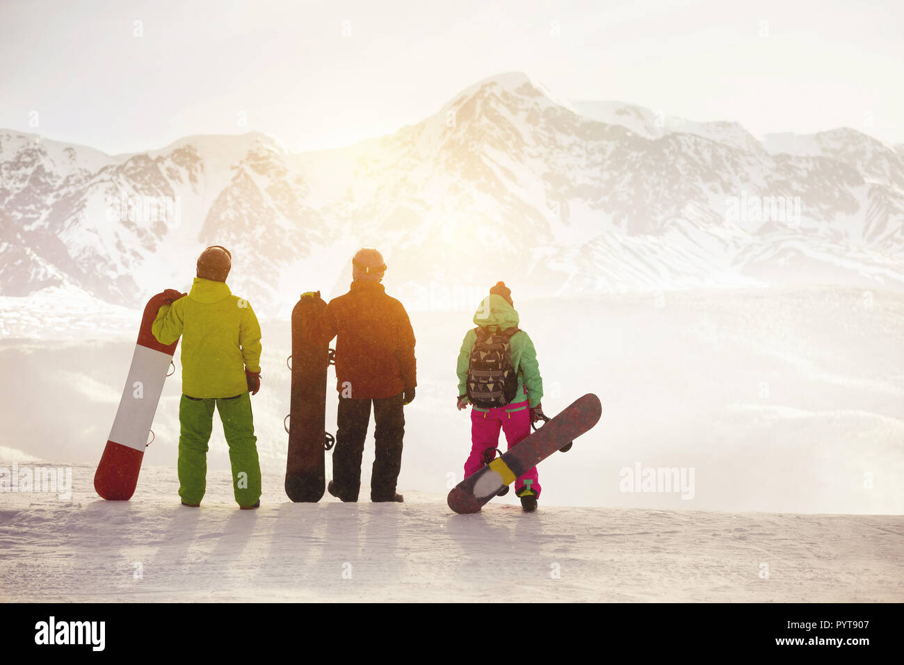 Drei Snowboarder steht mit Snowboards am Berg oben gegen Sonnenuntergang Sonne über Gletscher Stockfoto