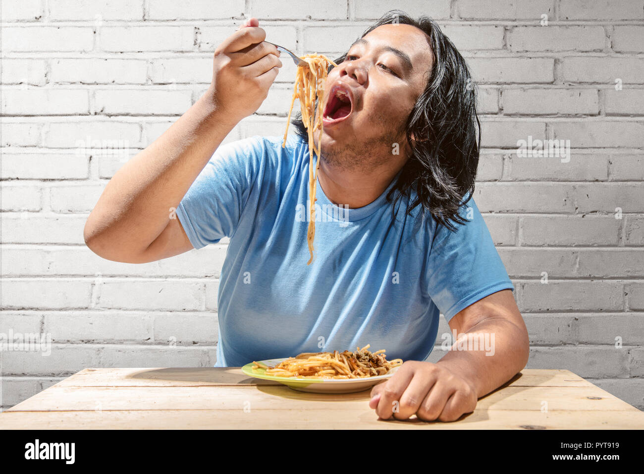 Asiatische fat man Essen fast food Spaghetti zu Hause. Fat Man Diät Konzept Stockfoto