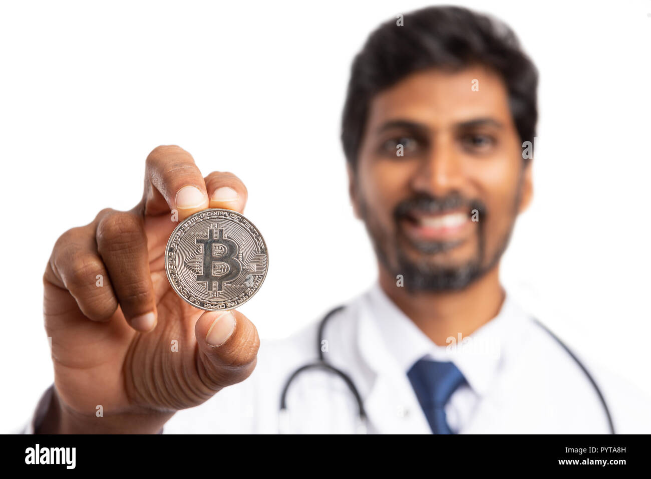 Indische männlichen Sanitäter oder Arzt präsentiert Silber bitcoin mit Fokus auf IT und unscharf Lächeln auf weißen isoliert Stockfoto