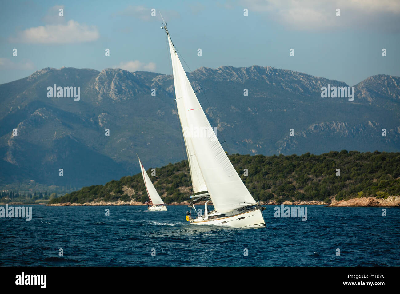 Yachtcharter Boote mit weissen Segeln in der Nähe der Felsen in der Ägäis. Segelregatta. Stockfoto