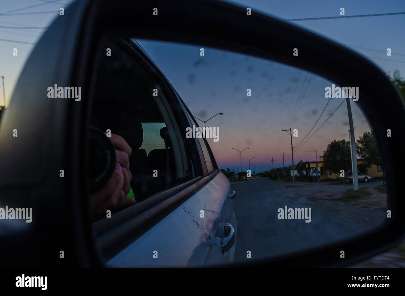 Straße von der Innenseite eines Autos und die Reflexion der Rückspiegel des Autos. Road Trip bei Sonnenuntergang, Sonnenuntergang aus dem Inneren des Autos. Stockfoto