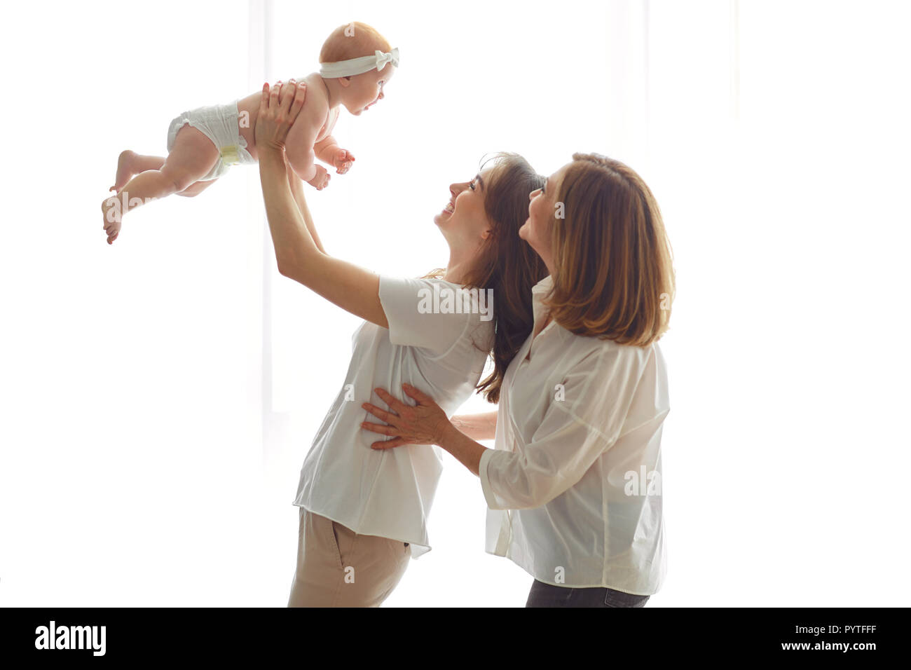 Mutter, Großmutter und Kleinkind auf Händen auf einem weißen Hintergrund. Eine Familie. Stockfoto