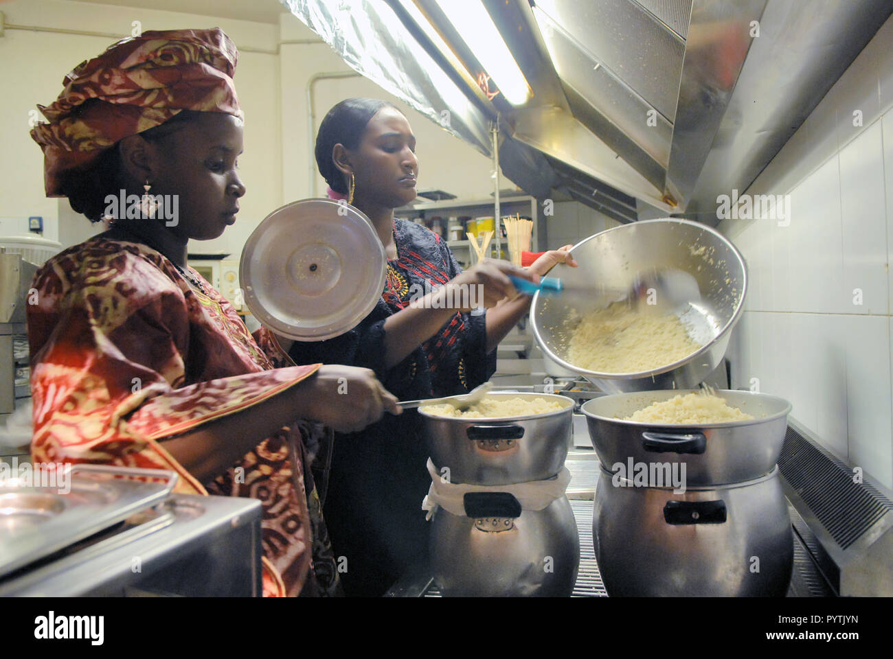 Tuareg einwandernde Gemeinschaft in Pordenone, Italien; zwei Frauen, Tounfana und Laglaga, in der Küche eines Restaurants bereiten traditionelle Lebensmittel für eine Party. Stockfoto