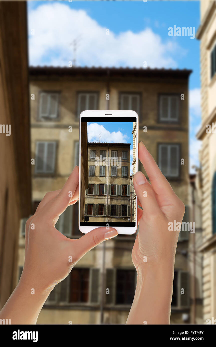 Ein Tourist ist ein Foto eines Teils der Fassade eines alten Wohnhauses in der Altstadt von Florenz, Italien auf einem Mobiltelefon Stockfoto