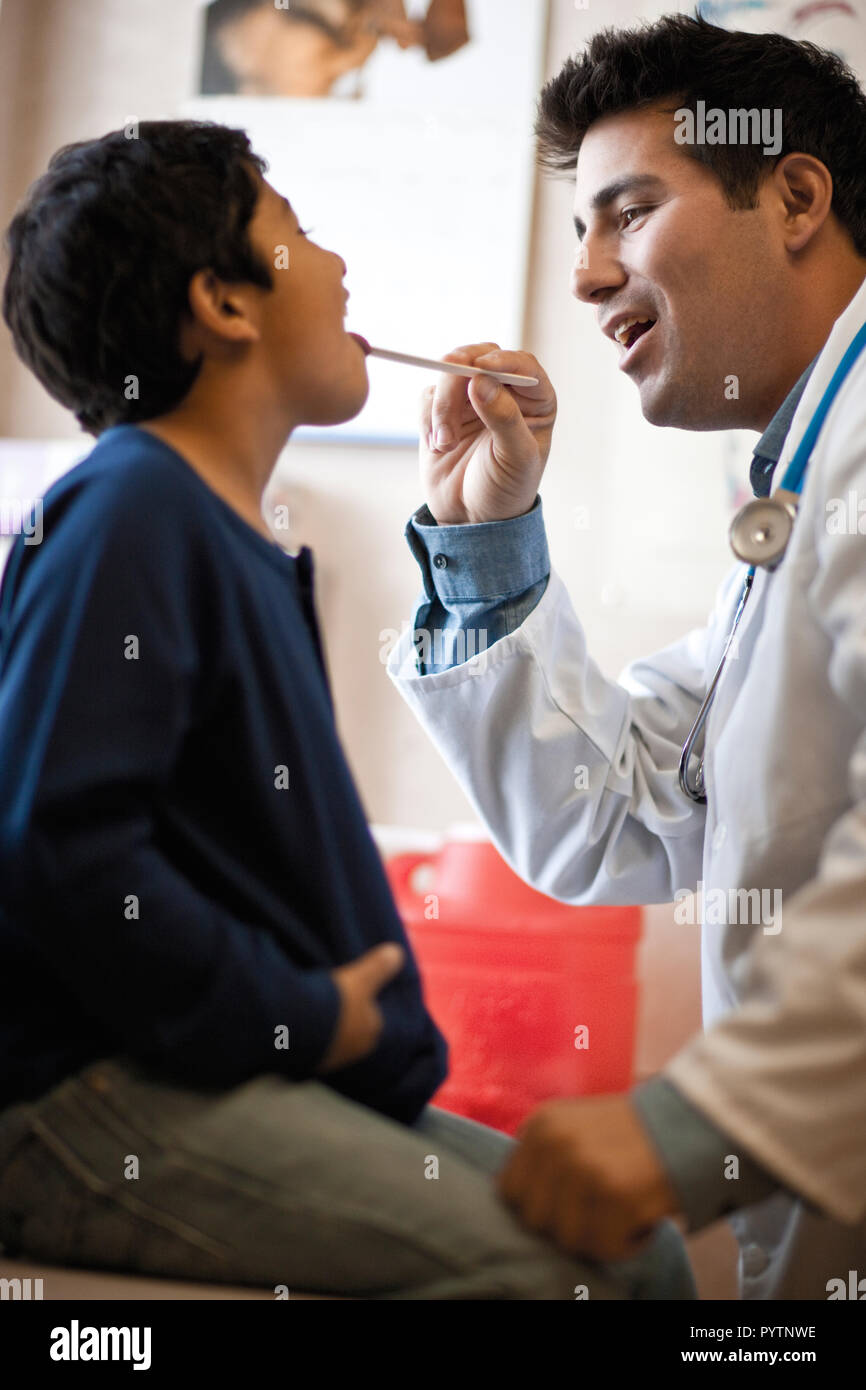 Der Arzt prüft junge Kehle mit zungenspatel. Stockfoto