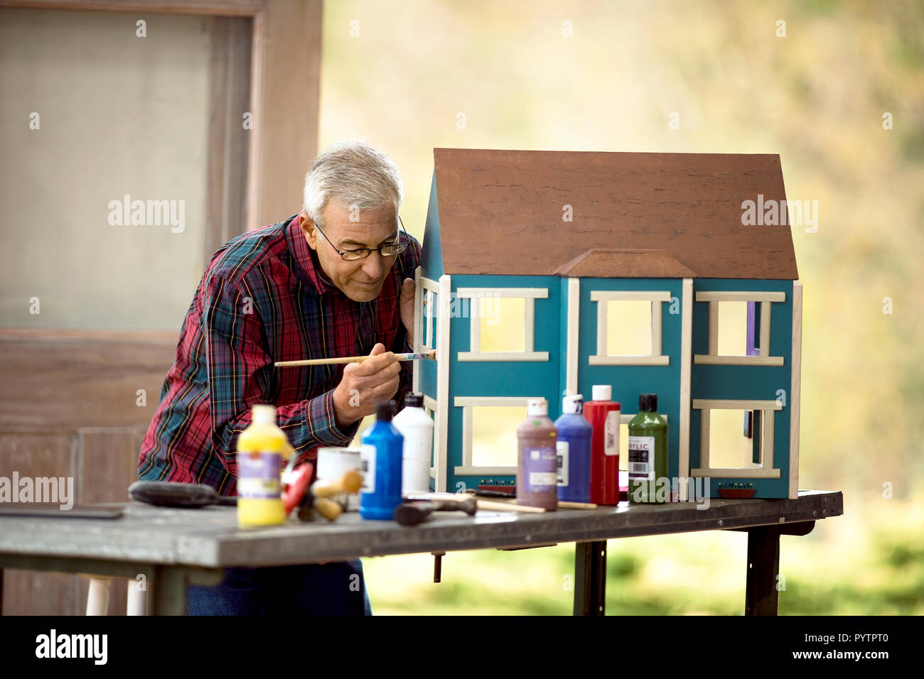 Nachdenklich älterer Mann Malerei ein Puppenhaus. Stockfoto